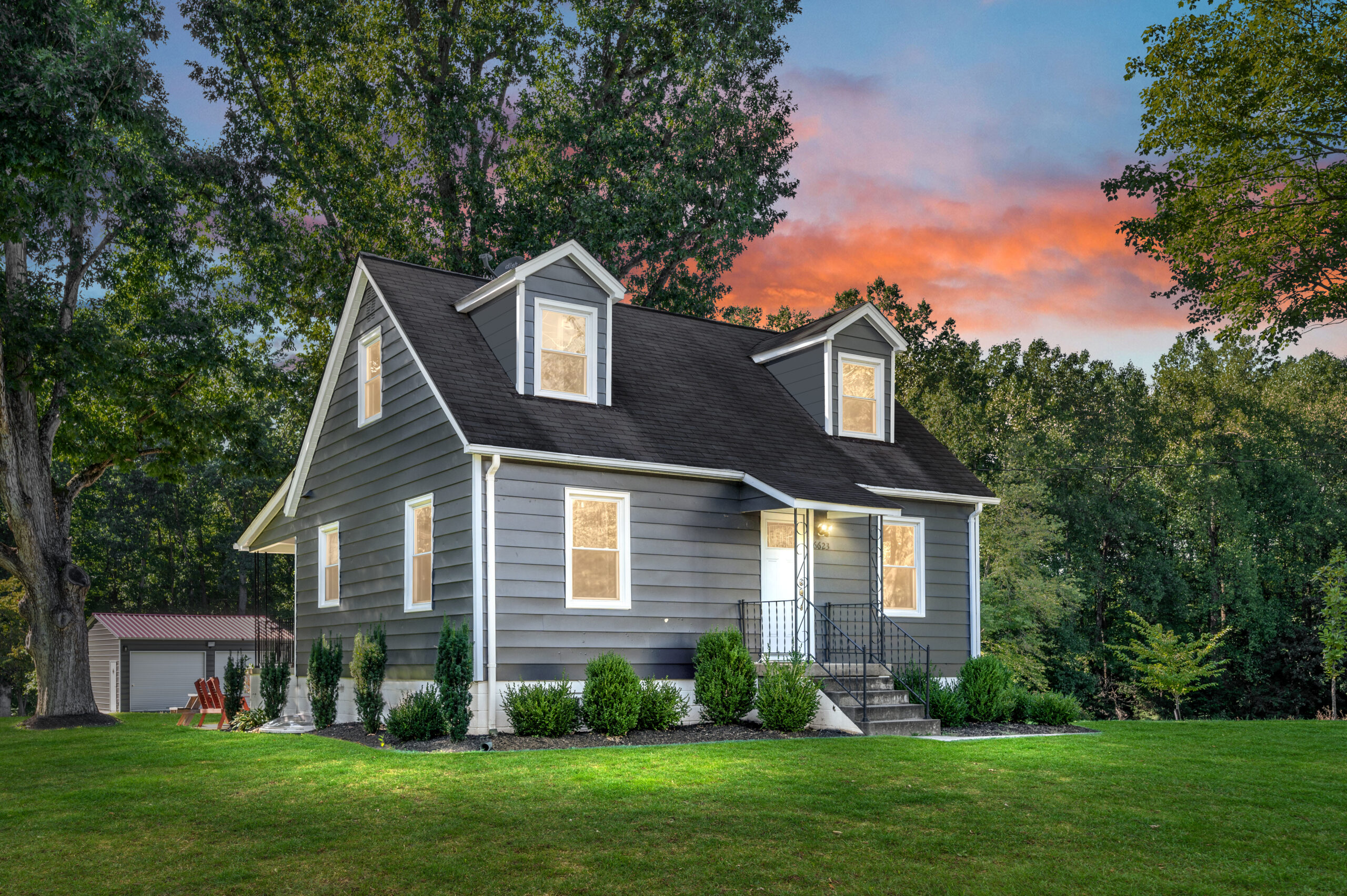 Gray Cape Cod style home surrounded by trees