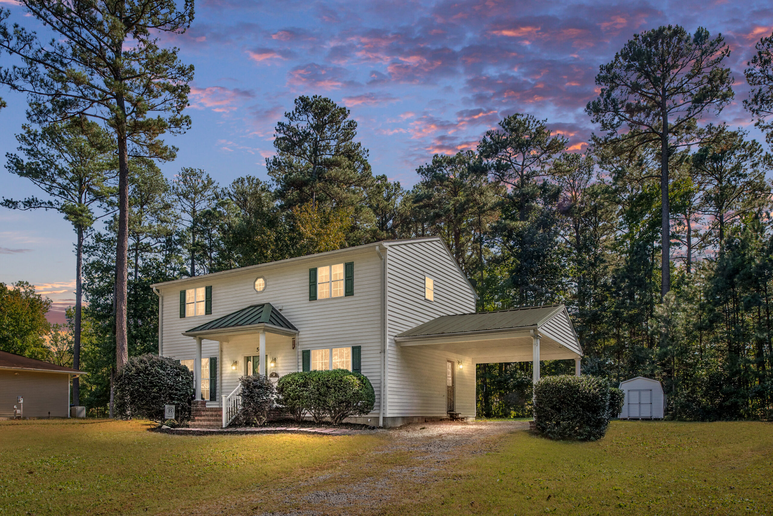 White two-story home with green front door and shutters; a waterfront community home for sale