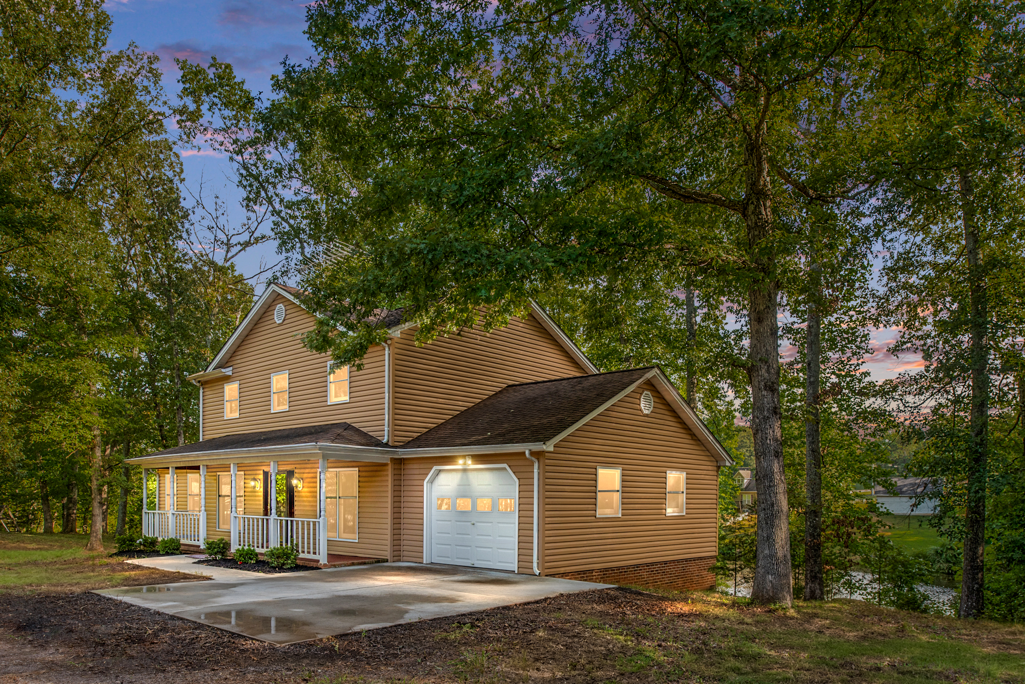 Tan colored waterfront home in Locust Grove surrounded by trees with a pond visible in the background